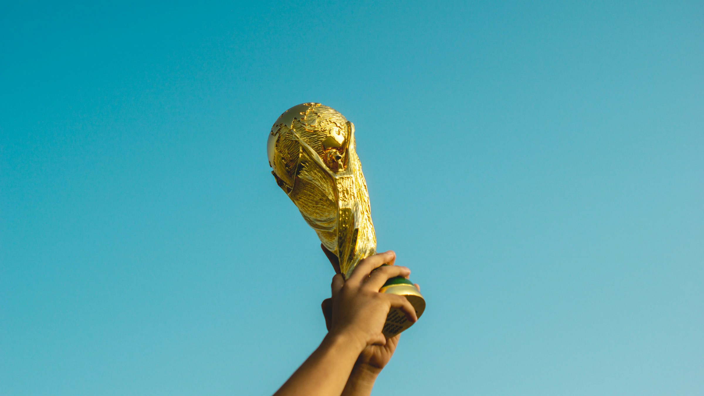 Gold World Cup trophy centered on a podium on a soccer field